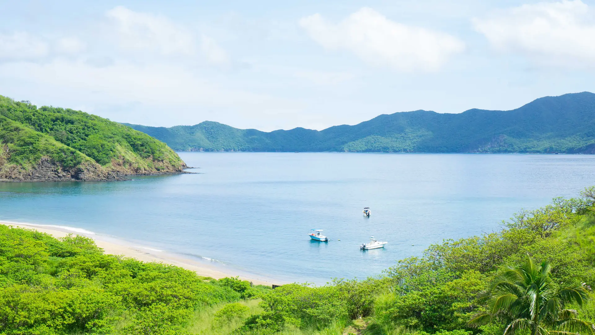 Calm turquoise bay with anchored boats in Guanacaste