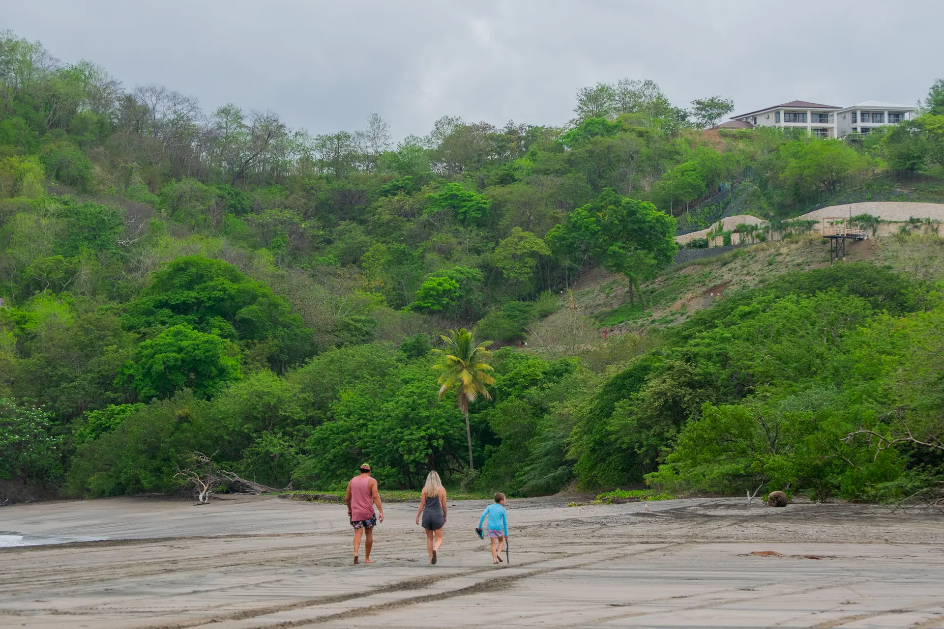 Neighbors strolling up the beach toward the green hills